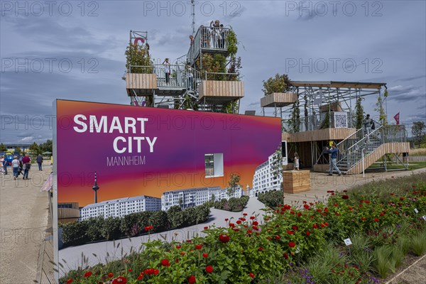 Sign saying Smart City Mannheim in front of viewing platforms on metal scaffolding overgrown with green plants at the Federal Horticultural Show