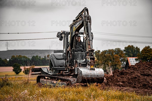 Black Yanmar mini tracked excavator during earthworks for house construction on building site