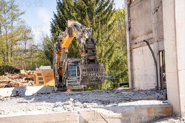 Yellow Liebherr crawler excavator with grapple recycling on demolition site