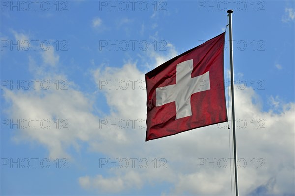 Swiss flag flapping in the wind against cloudy sky