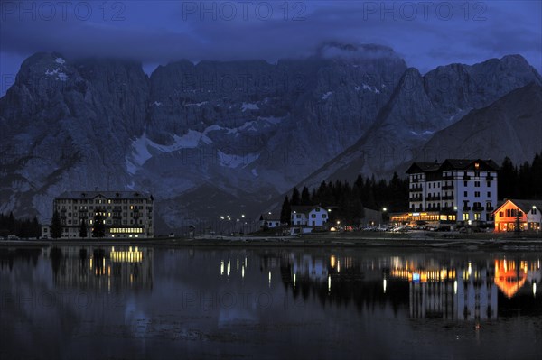 The mountain range Gruppo del Sorapis and hotels at night along lake Lago di Misurina in Auronzo di Cadore