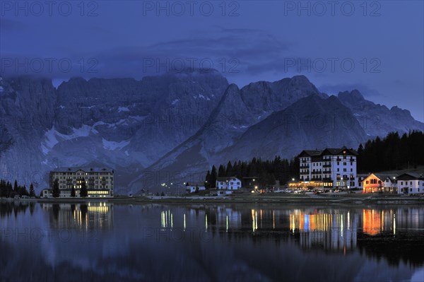 The mountain range Gruppo del Sorapis and hotels at night along lake Lago di Misurina in Auronzo di Cadore