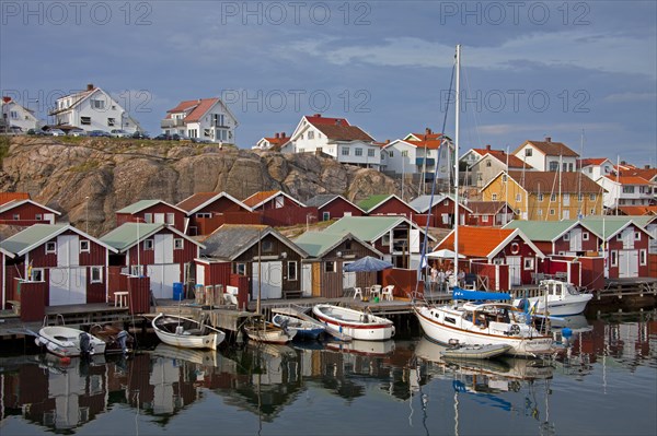 Colourful traditional fishing huts and boathouses along wooden pier at Smoegen