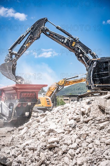 Black tracked excavator during demolition recycling on construction site