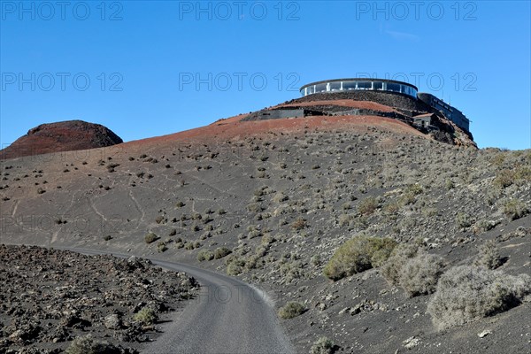 View of volcanic hilltop with tourist centre in Timanfaya National Park with panoramic restaurant El Diablo designed by Cesar Manrique