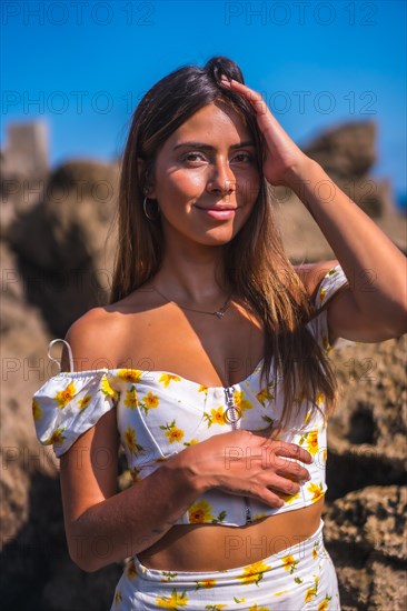 Portrait of a young woman in a white dress on the beach in summer