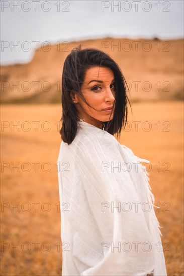 Portrait of a brunette Caucasian model girl in a white dress and a black bikini in a desert one summer afternoon