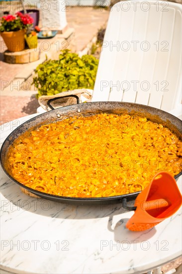 Valencian paella made on wood embers and vegetables on the restaurant table. Traditional Spanish Mediterranean food of fish and seafood