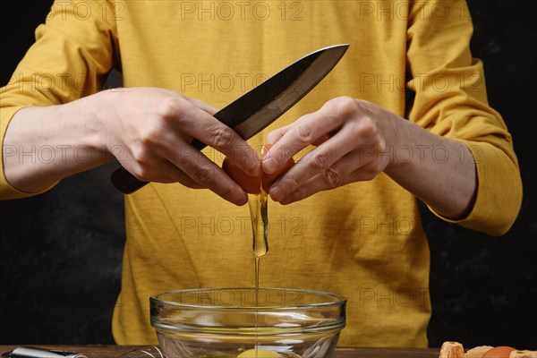 Unrecognizable man breaks eggs into a glass bowl to make an omelette