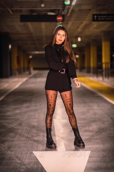 Young caucasian model with black jacket posing in an empty underground car park. Night urban session in the city