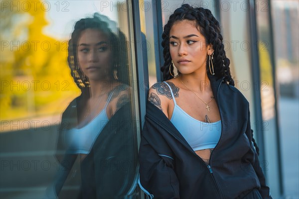 Urban session. Young woman of black ethnicity with long braids and with tattoos