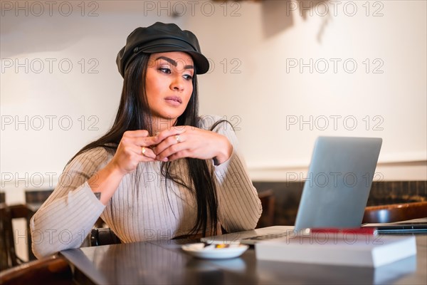 Latina brunette architect reading work emails with computer teleworking from a cafeteria on vacation