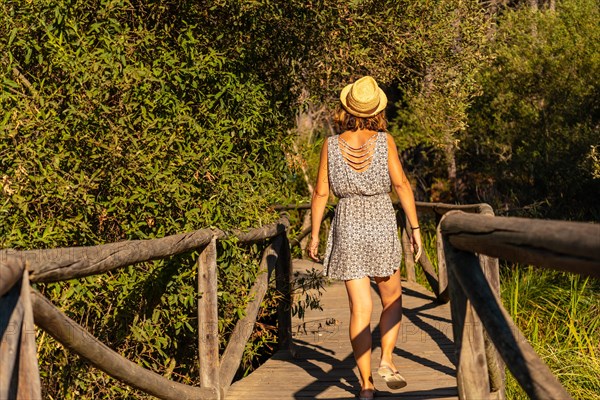 A young tourist walking along a wooden walkway in the Donana Natural Park