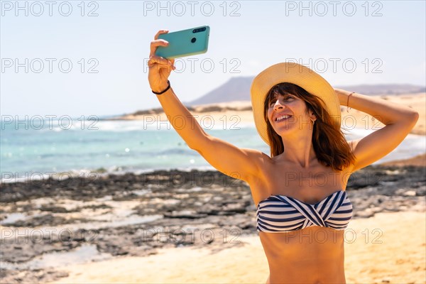 A young tourist taking a photo with the phone on the beaches of the Corralejo Natural Park