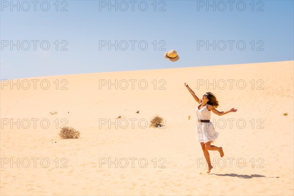Tourist throwing his hats up very happy in the dunes of the Corralejo Natural Park
