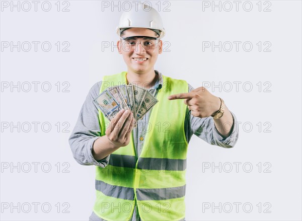 Smiling engineer builder holding and pointing money isolated. Handsome engineer showing and pointing money isolated