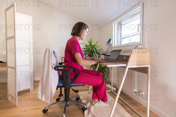 Profile photo of an adult nutritionist doctor using laptop while working from home