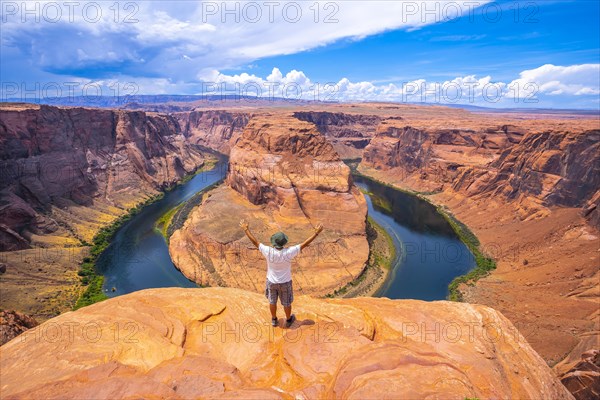 A young man in a white shirt and a green hat at Horseshoe Bend and the Colorado River in the background