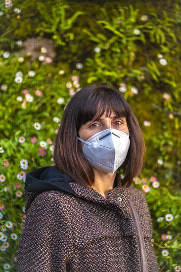 A young woman with a mask on her first walks in mistrust. First walks of the uncontrolled Covid-19 pandemic