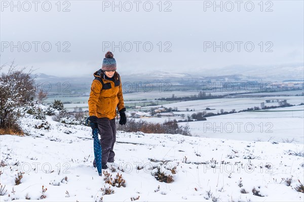 Young girl in yellow jacket playing in the snow with an umbrella. Snow in the town of Opakua near Vitoria in Araba