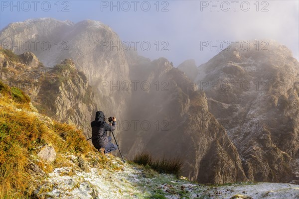 A photographer taking a photo with the tripod in the snowy winter sunset