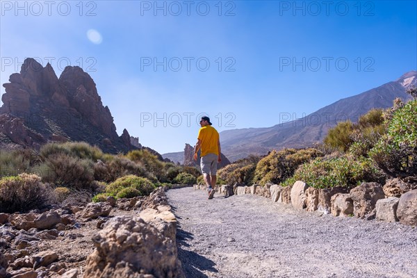 A tourist walking on the path between Roques de Gracia and Roque Cinchado in the natural area of Teide in Tenerife