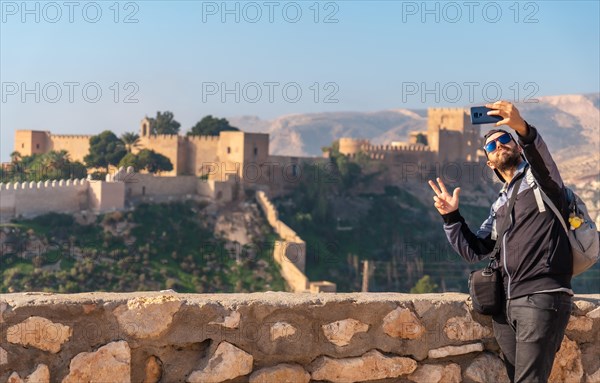 A young tourist taking a selfie at the viewpoint of Cerro San Cristobal de la Muralla de Jairan and the Alcazaba in the town of Almeria
