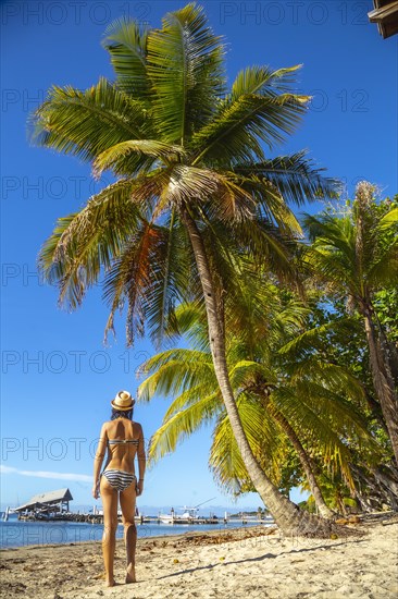 A young girl on top of a log dancing on West End beach on Roatan Island. Honduras