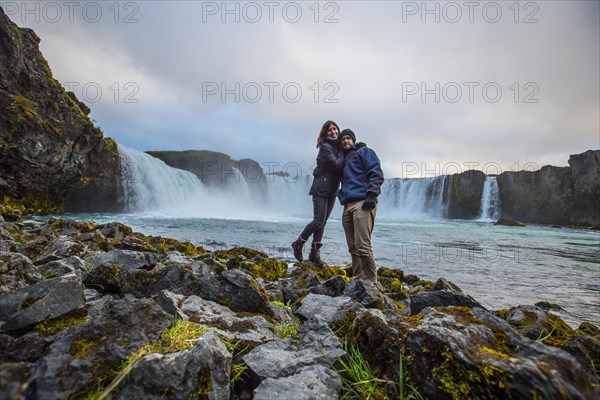 A young couple tourist looking at the Godafoss waterfall from above. Iceland