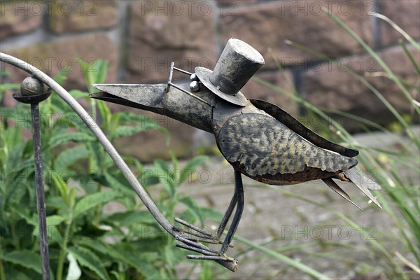 Raven as a tin figure in a garden