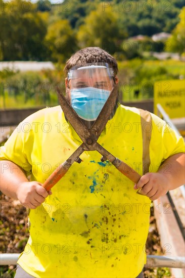 Worker in a recycling factory or clean point and garbage with a face mask and plastic protective screen