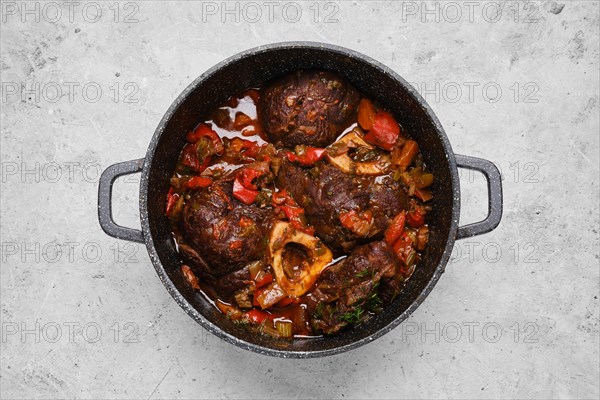 Top view of prepared beef ossobuco with chopped vegetables in a casserole