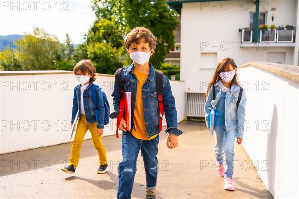 Three brothers with face masks ready to go back to school. New normality