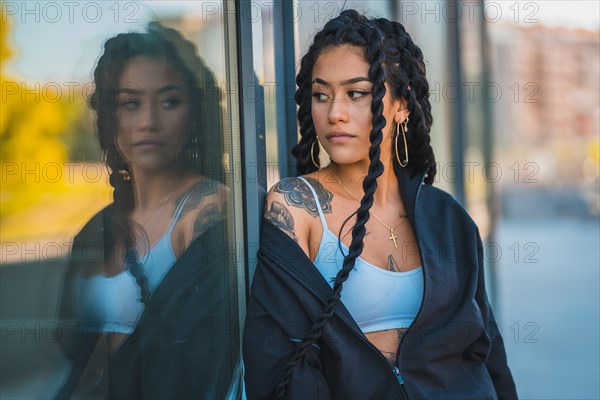 Urban session. Young woman of black ethnicity with long braids and with tattoos