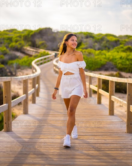 Lifestyle of a young brunette Caucasian enjoying the beach vacation in a white dress in summer