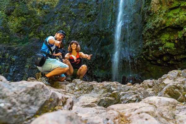 A family with their child in summer at the waterfall at Levada do Caldeirao Verde