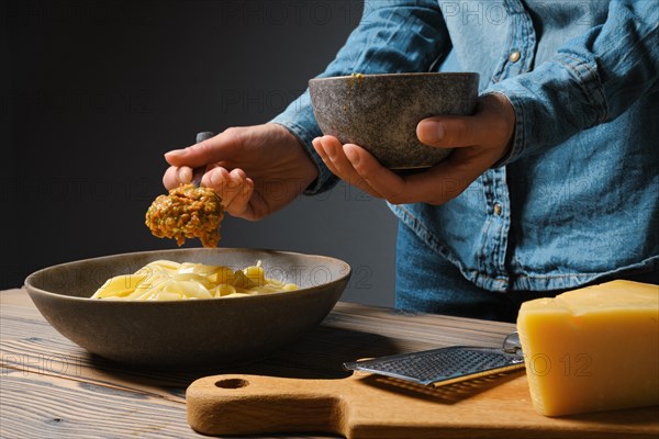 Low key photo of unrecognizable woman serve vegetable sauce in plate with pasta