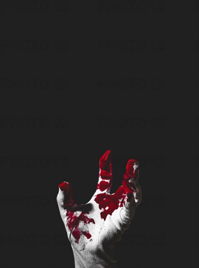 Reaching up hand in white glove with blood stains