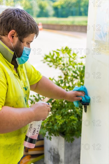 Worker in a recycling factory or clean point and garbage with a face mask and plastic protective screen