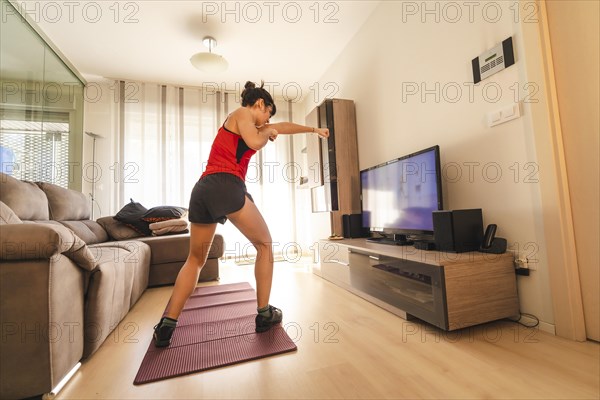 A young woman doing sports in her living room. Sport in the quarantine at home