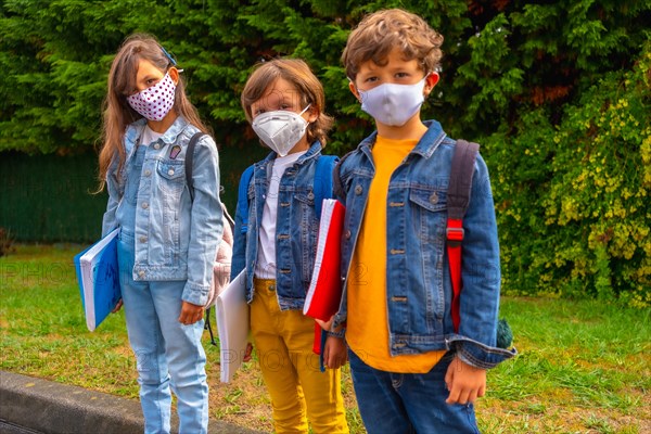 Three brothers with face masks ready to go back to school. New normality