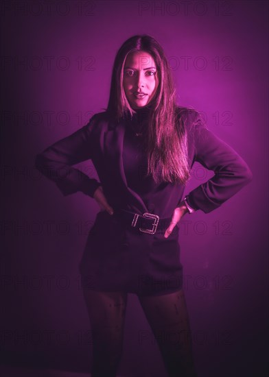 Young Caucasian model illuminated with pink neon lights. On a black wall background