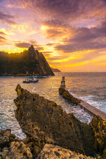 A boat leaving at sunset in the lighthouse of the municipality of Pasajes San Juan in Gipuzkoa. Basque Country