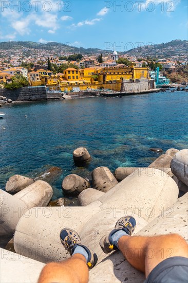 Sitting looking at yellow fort by the sea from Forte de Sao Tiago on Funchal beach. Madeira