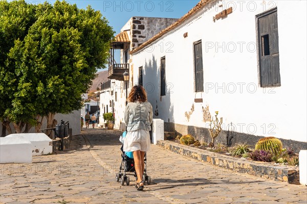 A young mother walking next to the white church of Betancuria