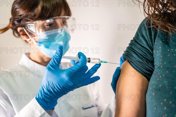 Female doctor with face mask applying the coronavirus vaccine