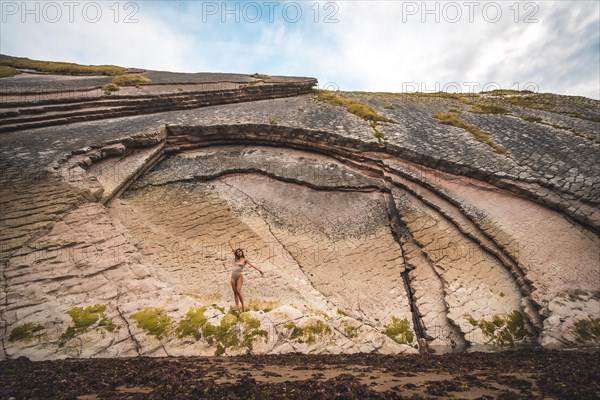 A dark-haired caucasian woman in a brown swimsuit on a natural background by the sea in the town of Zumaia