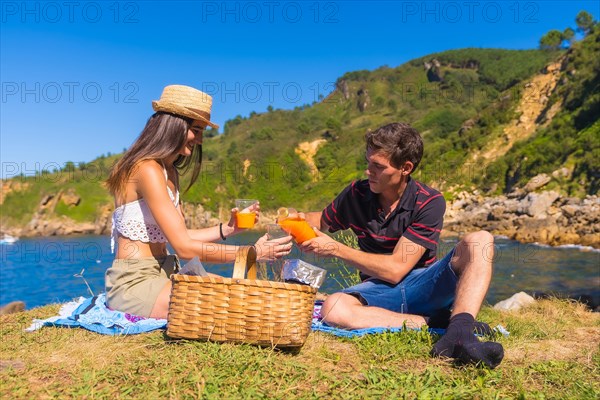 A young couple on a picnic in the mountains by the sea enjoying the summer