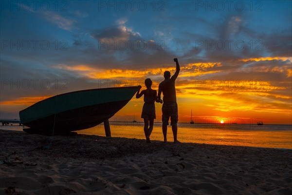 A couple watching the Roatan Sunset from West End. Honduras