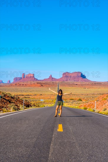 A young woman in a black T-shirt sitting on the road to Monument Valley. Utah